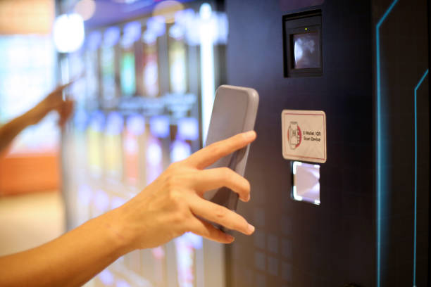 Main d’un client se dirigeant vers l’interface tactile d’un distributeur de coques de téléphone en libre-service dans un environnement commercial